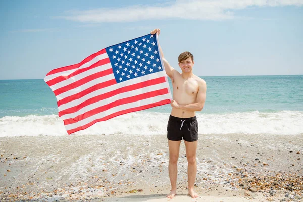 在沙滩上举着美国国旗的白种人男性 — 图库照片