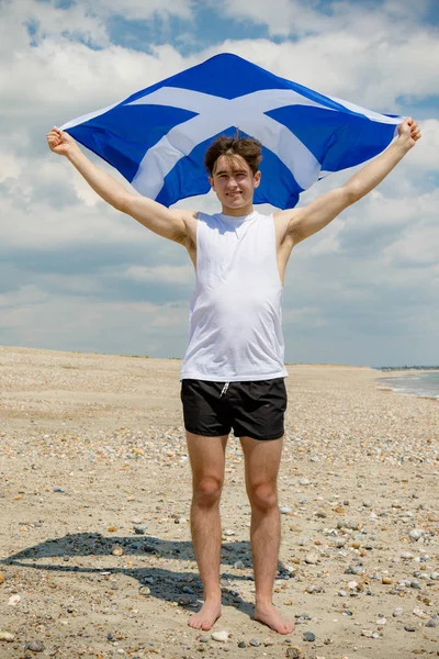Kaukasischer Mann am Strand mit einer schottischen Flagge — Stockfoto