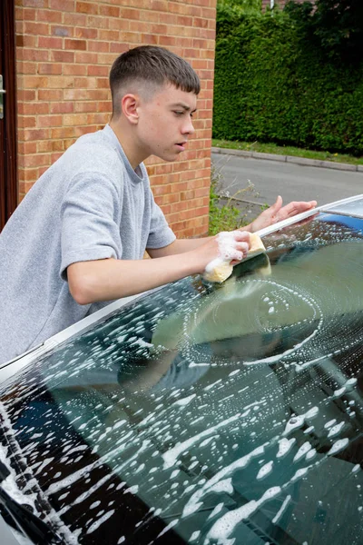 Хлопчик-підліток миє машину — стокове фото