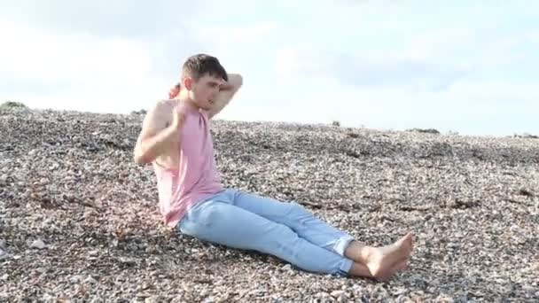 Junger Kaukasischer Erwachsener Mann Sitzt Einem Strand Und Zieht Sein — Stockvideo
