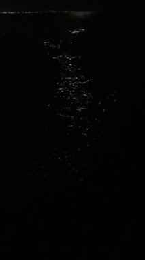 Ay geceleri denizin üzerinde gökyüzünde hareket ediyor. Deniz yüzeyindeki ay yolu. Ay doğuyor. Ay ışığı kadar yakın. Su yüzeyinde ay ışığı parlıyor. Doğa arkaplanı. Doğal arka plan. Dikey. Yüksek