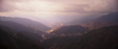 # Dağların üstünde zaman aşımlı sis ve gün doğumunda bulutların arasında güneş ışığı #