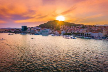 Split Riva 'nın altın saatindeki insansız hava aracı fotoğrafı rıhtım geçidini, palmiye ağaçlarını, tarihi eski kenti, Adriyatik Denizi' ni ve güzel bir yaz günbatımında ışıldayan gökyüzünü gösteriyor.