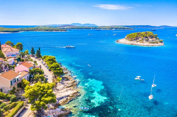 Hvar 'ın turkuaz Adriyatik suları, demirlemiş tekneleri, yemyeşil otlakları ve uzaktaki manzaralı Pzekeni Adaları takımadalarının insansız hava aracı fotoğrafı.