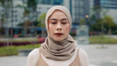 Şehir merkezinde tesettürlü kendinden emin genç Malezyalı bir kadının portresi duruyor. Müslüman kadın şehir ortamlarında modern yaşam tarzı ve gelenek toplantısını temsil ediyor. Güzel görünüş