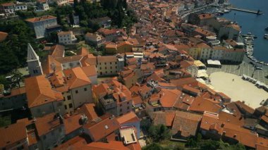 Terracotta çatıları gün ışığında parlayan kaldırımlı meydanın etrafında toplanır. Yat limanı deniz kenarına yakın teknelerle dolarken dar sokaklar yokuş aşağı gidiyor.