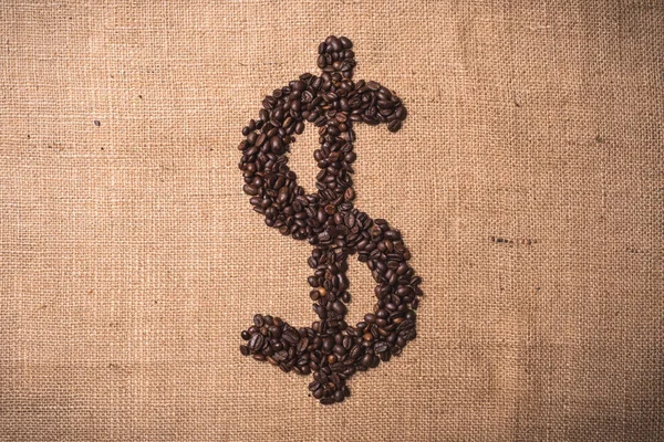 Dollar symbol written with toasted coffee beans on landscape composition