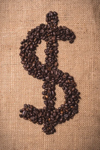 Dollar symbol written with toasted coffee beans on portrait composition