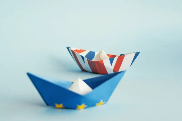 paper ships from the flags of the European Union and the UK on a blue background, concept of an agreement on Brexit