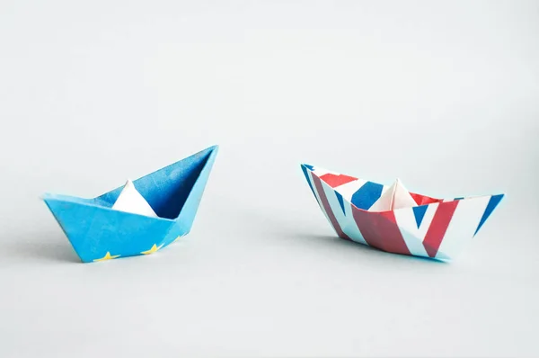 paper ships from the flags of the European Union and the UK on a blue background, concept of an agreement on Brexit