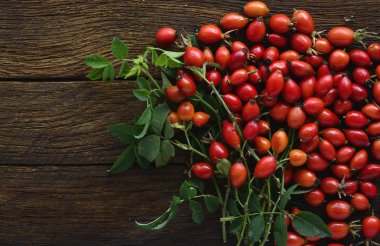 kırmızı köpek gül meyve ile kuşburnu dalları kahverengi ahşap bir masa üzerinde