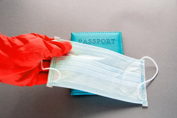 passport is hidden behind a face mask, a thermometer, hands in latex gloves. new flight rules travel concept traveling abroad during coronavirus pandemic