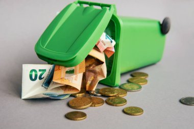 Euro banknotları ve sikkeleri olan çöp tenekesi, tıbbi maske, şırınga, termometre - kriz konsepti