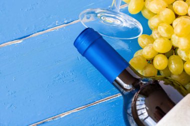 Taze beyaz üzümler ve mavi ahşap bir doku yüzeyinde bir şişe şarap ve cam. Reklam metni için alan
