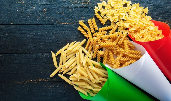 Variety types and shapes of raw Italian pasta in paper of Italy flag color - traditional italian Food background