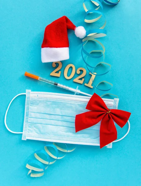 disposable hygienic face mask,sanitizer, 2021 christmas and new year decor on blue background. holidays self-isolation and pandemic covid concept