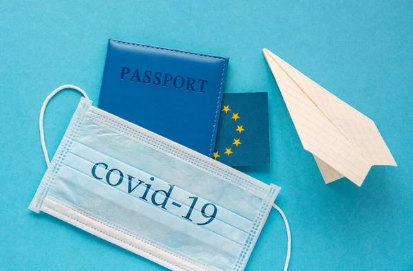 medical face mask, paper plane, passport and EU flag. travel concept traveling abroad during coronavirus pandemic