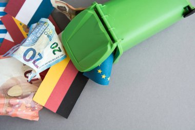 Euro banknotları ve sikkeleri olan çöp tenekesi, tıbbi maske, şırınga, termometre - kriz konsepti