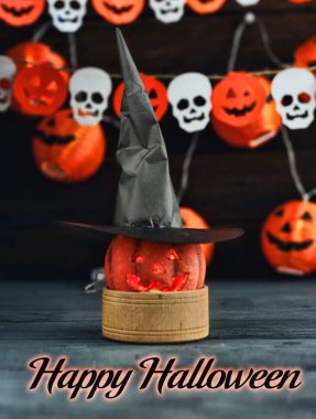 Cadılar Bayramı Jack o Fener kabağı ve cadı şapkası, arka planda yarasalardan ve kafatasından bir çelenk