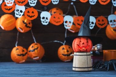 Cadılar Bayramı Jack o Fener kabağı ve cadı şapkası, arka planda yarasalardan ve kafatasından bir çelenk