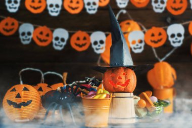 Cadılar Bayramı Jack o Fener kabağı ve cadı şapkası, arka planda yarasalardan ve kafatasından bir çelenk