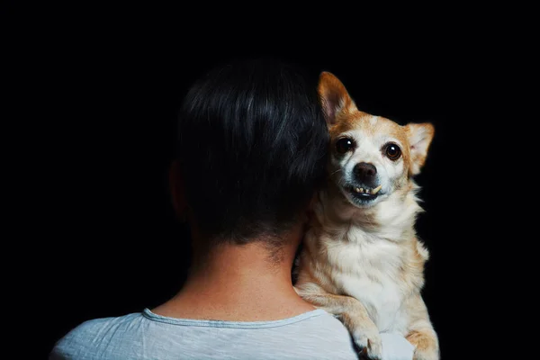 白いTシャツの男は黒の背景に隔離された肩の上に彼の古い悲しいペット犬を抱擁動物と所有者の間の愛と献身の感情 — ストック写真