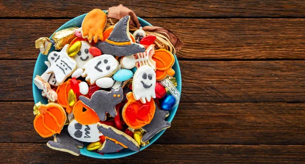 Halloween Jack o Lantern candy bowl with candy and halloween cookies Trick or Treat on black wooden background