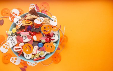 Cadılar Bayramı arkaplanınız kutlu olsun, Jack o Lantern şeker kasesi şekerli ve Cadılar Bayramı kurabiyeli şaka ya da şeker etrafınız dekoratif örümcekler, yarasalar, kafataslarıyla çevrili.