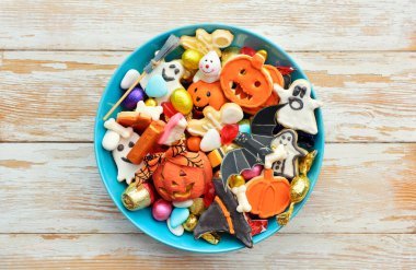 Cadılar Bayramı arkaplanınız kutlu olsun, Jack o Lantern şeker kasesi şekerli ve Cadılar Bayramı kurabiyeli şaka ya da şeker etrafınız dekoratif örümcekler, yarasalar, kafataslarıyla çevrili.