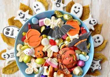 Cadılar Bayramı arkaplanınız kutlu olsun, Jack o Lantern şeker kasesi şekerli ve Cadılar Bayramı kurabiyeli şaka ya da şeker etrafınız dekoratif örümcekler, yarasalar, kafataslarıyla çevrili.