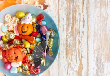 Cadılar Bayramı arkaplanınız kutlu olsun, Jack o Lantern şeker kasesi şekerli ve Cadılar Bayramı kurabiyeli şaka ya da şeker etrafınız dekoratif örümcekler, yarasalar, kafataslarıyla çevrili.