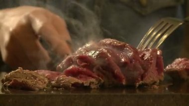 Restorandaki kız sıcak bir taşın üzerinde et hazırlıyor.