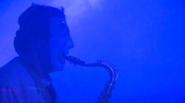 İnsanlar kulüpte müzikle dans ediyor. Saksafon çalmak ve dans etmek.