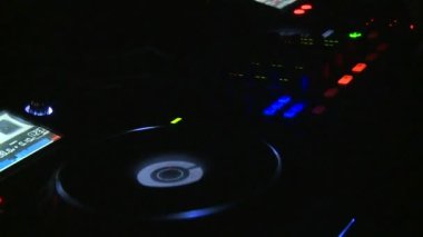 Tekno parti. İnsanlar dans eder, DJ çalar. Her yerde renkli ışıklar