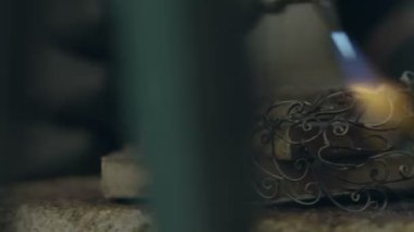 Kuyumcu gümüşten mücevher yapar. Kuyumcu gümüşü eritiyor, üzerinde desenler oluşturuyor, öğütüyor, kesiyor ve matkaplar yapıyor. iş gazı meşalesi