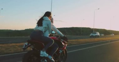 Gün batımında motosiklet süren aşık çift.