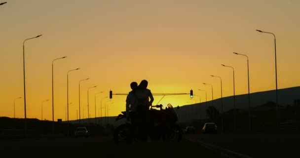 Verliebtes Paar Steht Bei Sonnenuntergang Neben Einem Motorrad — Stockvideo
