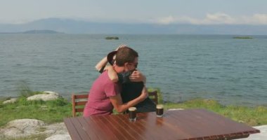 Birbirini seven bir çift deniz kenarında oturuyor. Manzaraya hayran olun, sarılın, öpüşün, konuşun ve eğlenin.