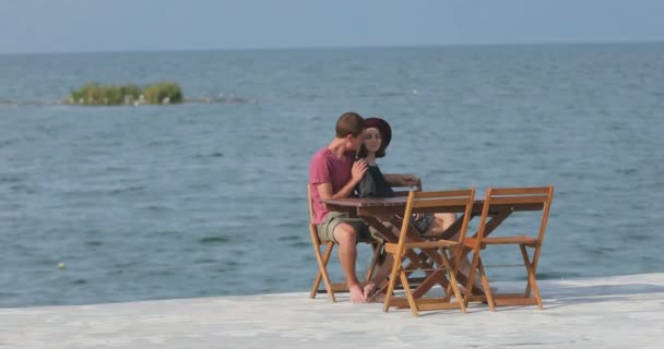 海の近くのマリーナに座って愛のカップル 風景を鑑賞 お互いに話をし 楽しみを持っています — ストック動画