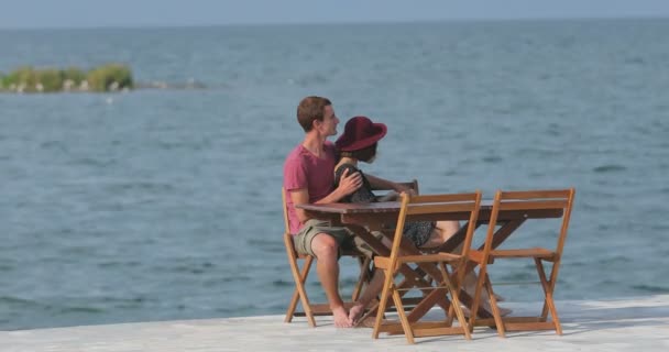 情侣们坐在海边的码头旁谈恋爱 欣赏风景 彼此交谈 玩得开心 — 图库视频影像