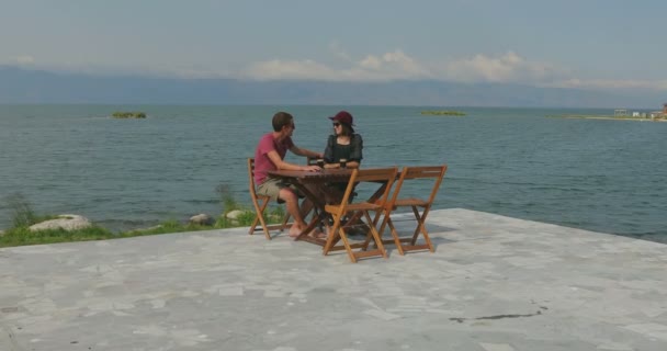 海の近くのマリーナに座って愛のカップル 風景を鑑賞 お互いに話をし 楽しみを持っています — ストック動画