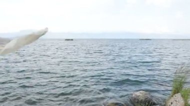 Kız elinde şalla zarifçe hareket ediyor. Sahilde bekliyorum.