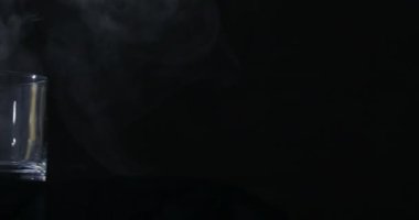 Boş bir viski, siyah bir arka planda alkol bardağı ve yüzen bir duman.