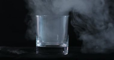 Boş bir viski, siyah bir arka planda alkol bardağı ve yüzen bir duman.