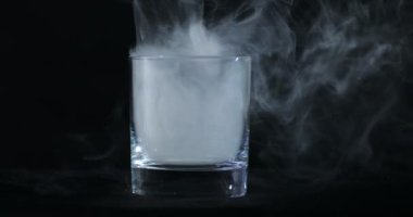 Boş bir viski, siyah bir arka planda alkol bardağı ve yüzen bir duman.