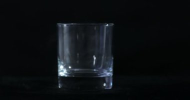 Boş bir viski, siyah bir arka planda alkol bardağı ve yüzen bir duman.