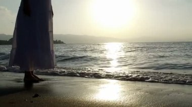 Gün batımında kıyı boyunca ağır çekimde koşan bir kızın görüntüsü..