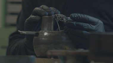 Kuyumcu gümüşten mücevher yapar. Kuyumcu gümüşü eritiyor, üzerinde desenler oluşturuyor, öğütüyor, kesiyor ve matkaplar yapıyor. iş gazı meşalesi