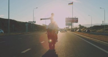 Gün batımında motosiklet süren aşık çift.