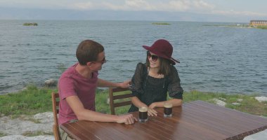 Birbirini seven bir çift deniz kenarında oturuyor. Manzaraya hayran olun, sarılın, öpüşün, konuşun ve eğlenin.